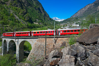 Train passing by mountains against blue sky