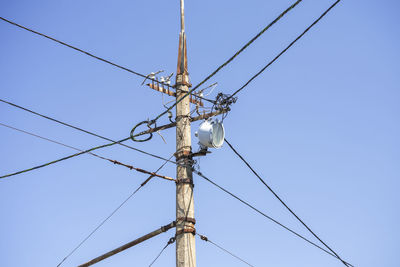 Low angle view of electricity pylon against clear sky