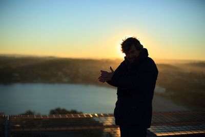 Woman standing on landscape at sunset