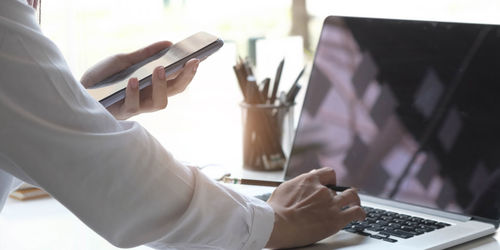 Midsection of man holding mobile phone