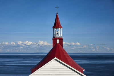 Close-up of red bell tower by sea against sky