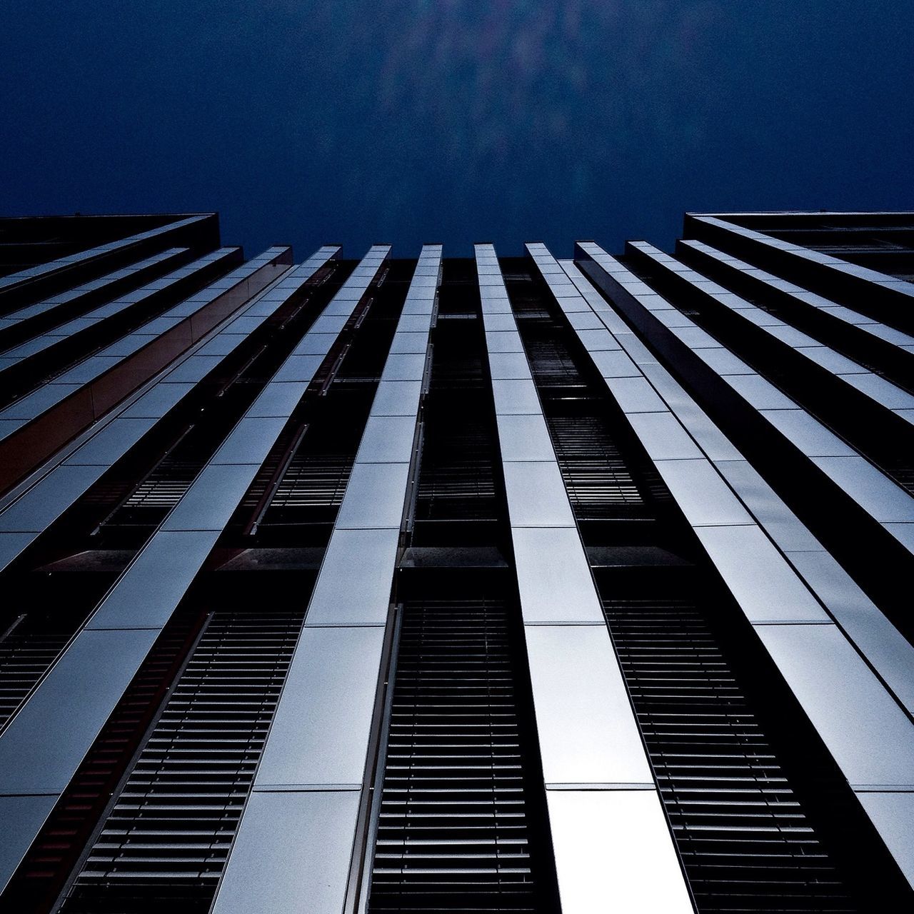 low angle view, architecture, built structure, building exterior, modern, office building, skyscraper, tall - high, city, tower, sky, building, glass - material, tall, reflection, outdoors, blue, day, no people, city life