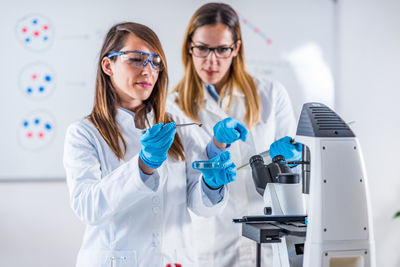 Female scientists examining chemical in laboratory