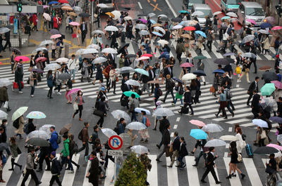 High angle view of people with umbrellas crossing road in city