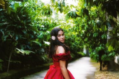 Portrait of young woman standing against plants