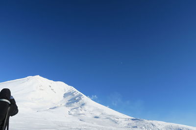 Man on snowcapped mountains against blue sky