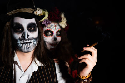 Portrait of woman wearing mask against black background