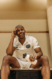 Low angle view of male athlete taking rest during break time sitting at sports court