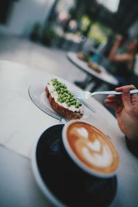 Midsection of person holding coffee cup on table