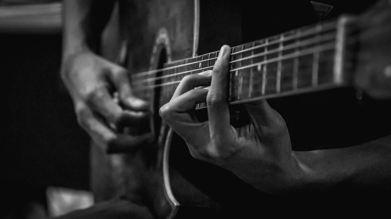 MIDSECTION OF MAN PLAYING GUITAR AT MUSIC CONCERT