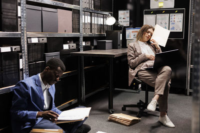 Side view of young woman using laptop while sitting in office