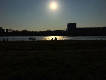 Scenic view of river amidst silhouette field against sky