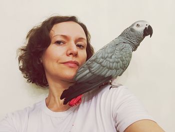 Woman with bird against white wall