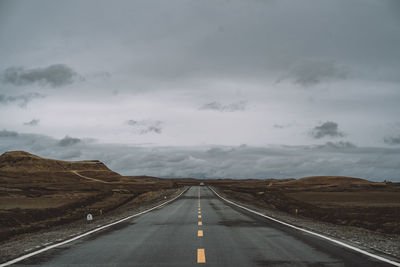 Empty road amidst landscape against sky