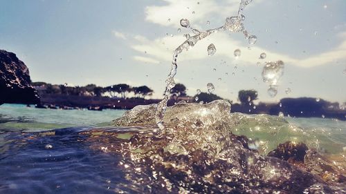 Close-up of water splashing in sea against sky