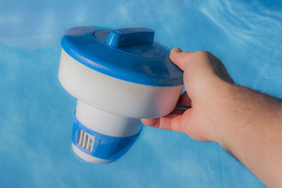 Cropped hand holding distributor float for chlorine