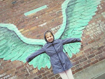 Portrait of girl standing against brick wall