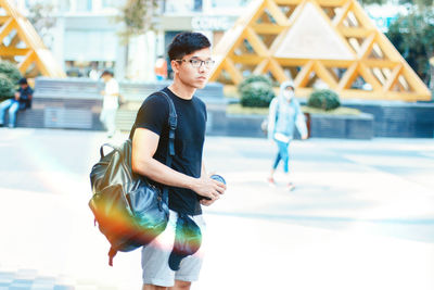Young man with backpack on road in city