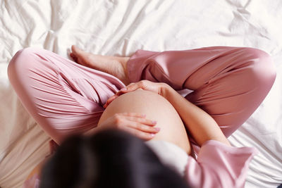 Pregnant woman sitting on bed at home