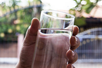 Cropped hand of man holding water in glass