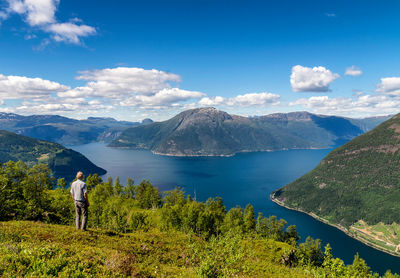 Woman standing by lake and mountains against sky