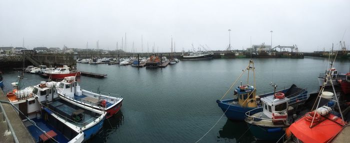 Panoramic view of boats moored at harbor in sea against sky