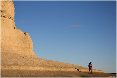 Woman on desert against clear blue sky