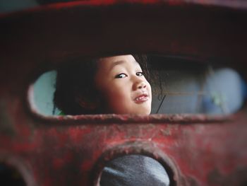Portrait of cute girl smiling seen through rusty metal