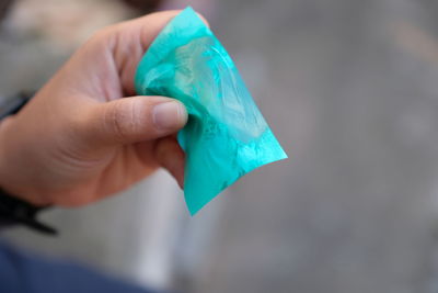 Close-up of human hand holding blue paper