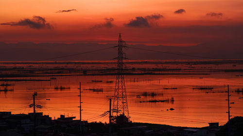 Silhouette electricity pylon against romantic sky at sunrise