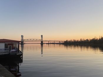 Bridge over river against clear sky during sunset