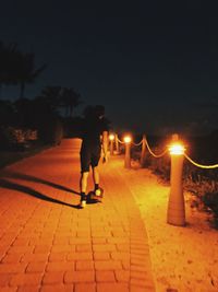 Man walking on illuminated street at night