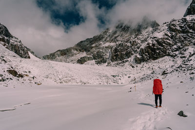 Rear view of man walking on snow covered mountain