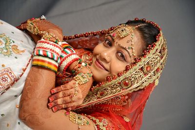 Close-up portrait of smiling young bride standing against wall