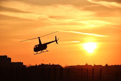 Low angle view of silhouette helicopter against sky during sunset