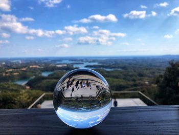 Close-up of glass on landscape against sky