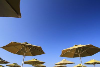 Low angle view of umbrellas against blue sky