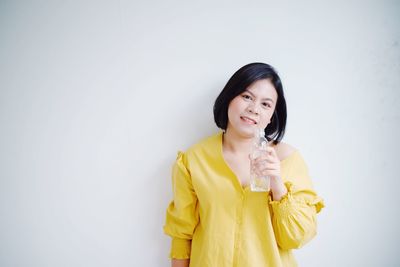 Smiling young woman standing against white background