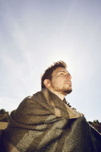 Man with shawl sitting on bench at field