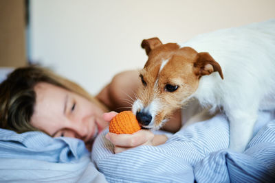 Woman lying in bed and playing with her dog, lazy weekend, morning relax
