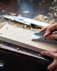 Wood shavings carpenter working with a metal spokeshave and a blurry background.