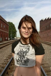 Portrait of young woman standing against sky