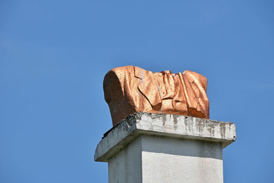 Low angle view of broken bust monument against clear blue sky