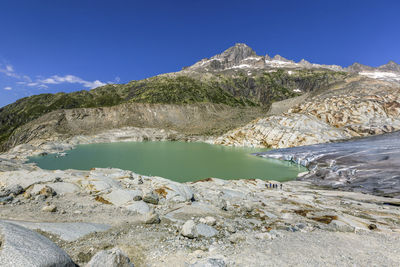 Scenic view of lake and mountains against blue sky