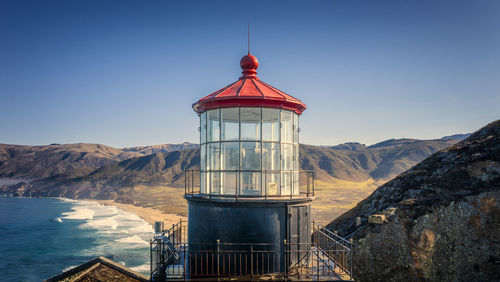 Lighthouse by sea against sky