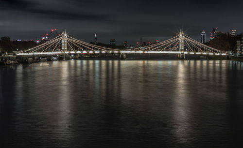 Illuminated bridge over river at night