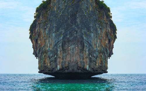 Rock formation in sea against sky