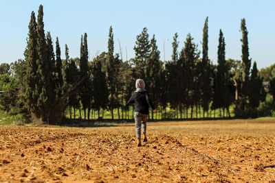 Full length rear view of woman running on field at park