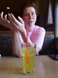 Close-up portrait of young woman with drink on table