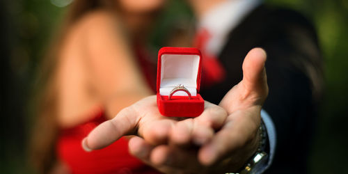 Midsection of bride and groom holding wedding ring